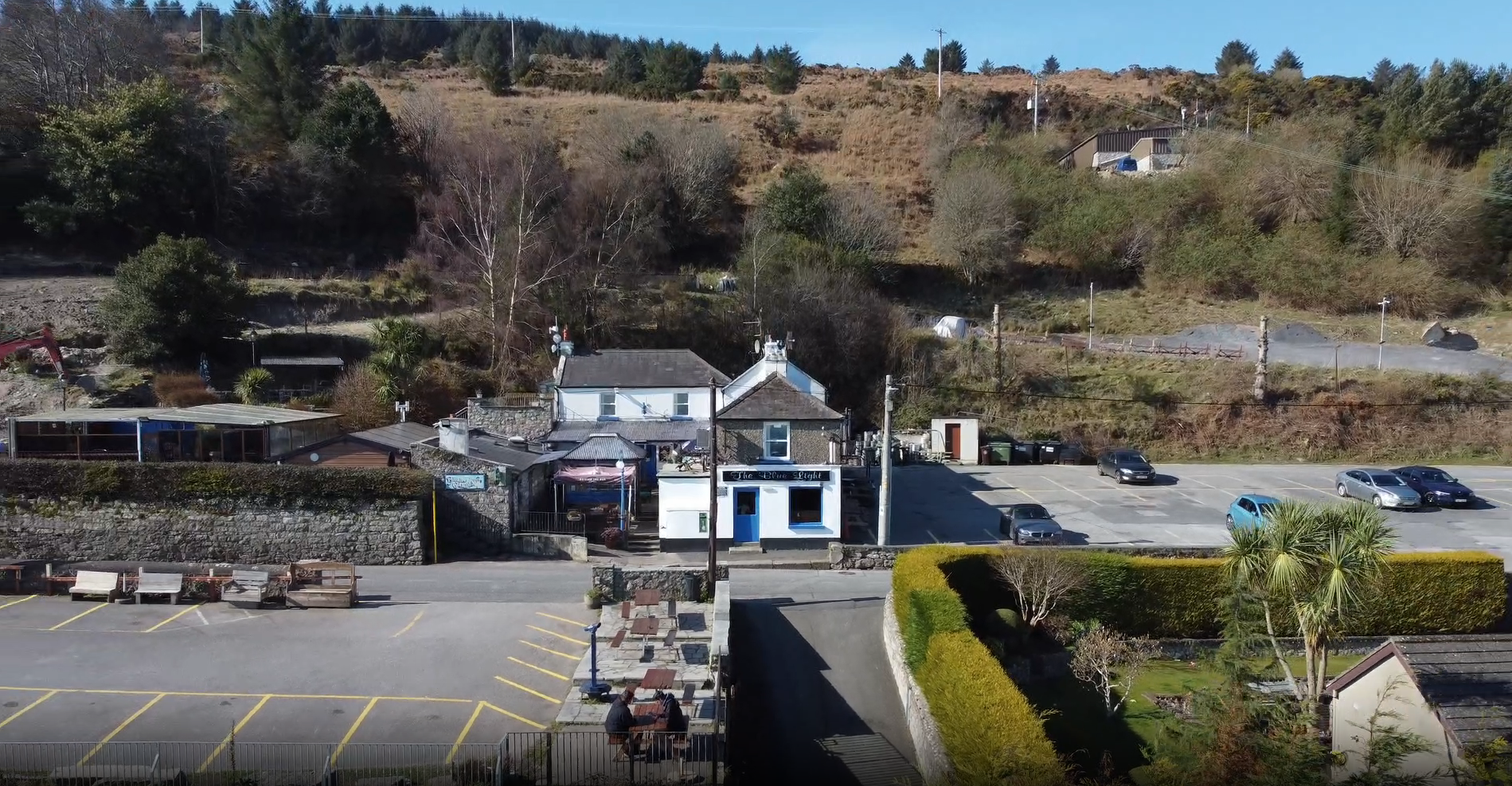 The Blue Light pub from above: the white building, its car park and the hillside behind it